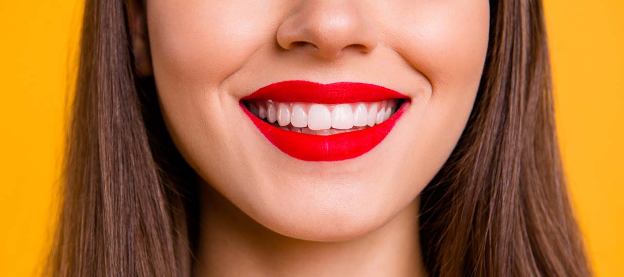 Frau lächelt mit roten Lippenstift und sauberen weißen Zähnen