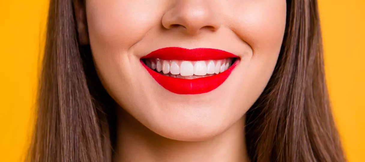 Frau lächelt mit roten Lippenstift und sauberen weißen Zähnen